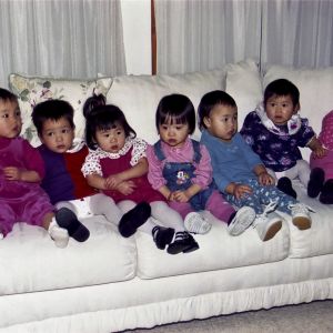 Seven recently adopted Chinese children hold still long enough for a photograph. The parents of these children, including the photographer, whose daughter, Shana, sits third from left, were celebrating the arrival of the newest members of their families in 1998.