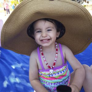 Aya, the young daughter of Syrian refugees, dons a big sun hat and flashes a huge smile during a hot day in Hood River, Oregon. The family came to the United States in 2016.